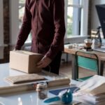 Person packar en kartong bland emballage och arbetsmaterial