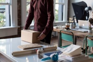 Person packar en kartong bland emballage och arbetsmaterial