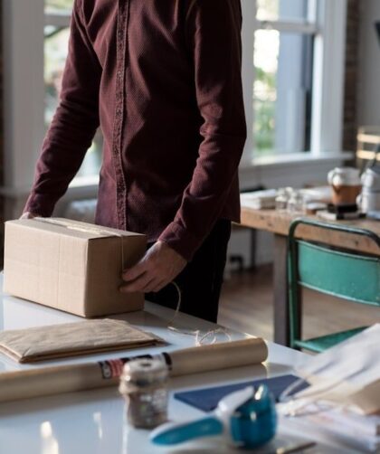 Person packar en kartong bland emballage och arbetsmaterial