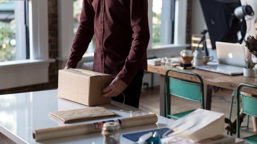 Person packar en kartong bland emballage och arbetsmaterial